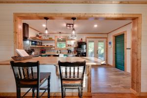 a kitchen with a large island with two chairs at Charming Eagletown Home with Deck and Private Hot Tub! in Eagletown