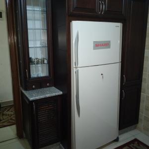 um frigorífico branco numa cozinha ao lado de um armário em عمان الجاردنز خلف بن العميد em Amã