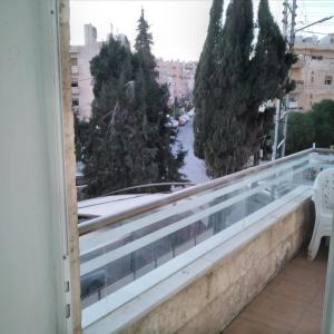 einen Balkon mit Blick auf Bäume und eine Straße in der Unterkunft عمان الجاردنز خلف بن العميد in Amman
