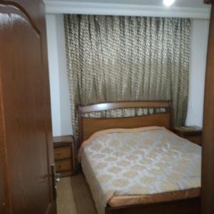 um pequeno quarto com uma cama e uma porta em عمان الجاردنز خلف بن العميد em Amã
