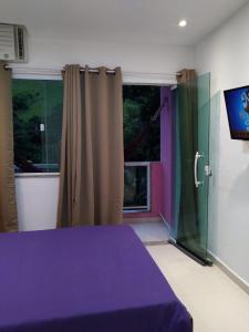 a bedroom with a purple bed and a window at Flat Três Praias in Angra dos Reis