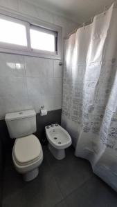 een badkamer met een toilet en een douchegordijn bij Departamento dos ambientes. in Castelar