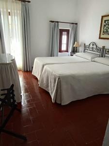 a bedroom with two beds with white sheets at Hostal Gran Capitan in Chipiona