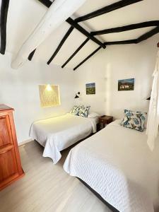 two beds in a room with white walls at Hospedaje Casa Santa Isabel in Villa de Leyva