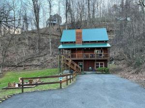 ein Haus mit einem grünen Dach und einer Auffahrt in der Unterkunft Stairway to Heaven - 3 Master Suite, Location, Privacy, Firepit in Gatlinburg