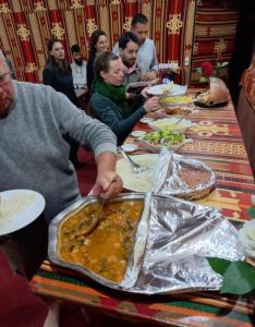 a group of people sitting around a table eating food at Wadi Rum Heaven Camp in Wadi Rum