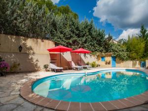 a swimming pool with two umbrellas and a patio at Les Iris in Lorgues