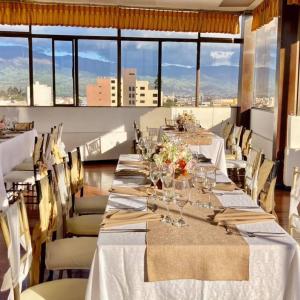 uma sala de jantar com mesas longas, cadeiras e janelas em Hotel El Cisne Internacional em Riobamba