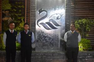 a group of three men standing in front of a sign at Hotel El Cisne Internacional in Riobamba