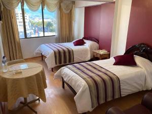 um quarto de hotel com duas camas e uma mesa em Hotel El Cisne Internacional em Riobamba