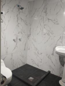 a white bathroom with a toilet and a sink at PROVENZA HOTEL & SUiTES in Atlixco