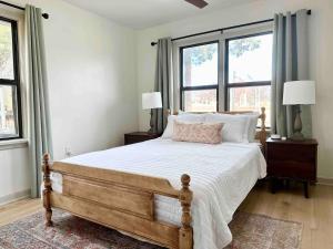 a bedroom with a bed with white sheets and windows at Campus Cottage Kng Bed! Walk To Uco And Downtown in Edmond