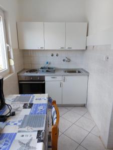 cocina con armarios blancos, mesa y fregadero en Apartments with a parking space Pisak, Omis - 1009, en Pisak