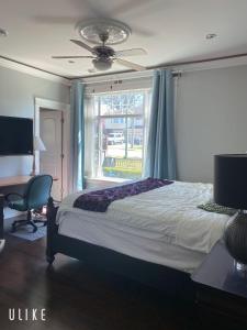 een slaapkamer met een bed, een plafondventilator en een raam bij Comfortable suite for guests to use independently in Burnaby
