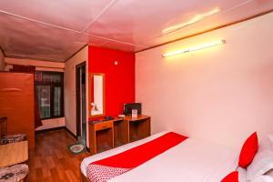 a bedroom with red walls and a bed with a desk at OYO Flagship View Point Resort in Nainital