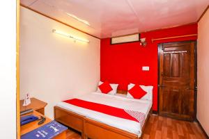 a bedroom with a bed with a red wall at OYO Flagship View Point Resort in Nainital