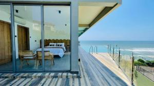 1 dormitorio con paredes de cristal y vistas al océano en Loku, en Matara