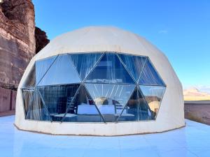 une maison en forme de dôme avec des fenêtres en verre dans le désert dans l'établissement Desert heart camp, à Wadi Rum