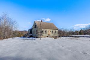 a house in the snow in front of a driveway at Charming Lovell Farmhouse - 17 Acres with Mtn Views! in Lovell
