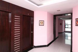 a corridor in a building with pink walls and wooden doors at SPOT ON Hotel Center Point in Rāmpura