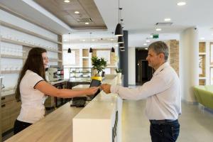 a man and a woman shaking hands at a counter at Family-Hotel in Balástya