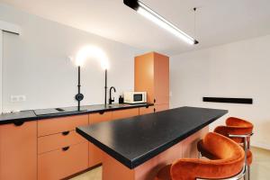 uma cozinha com armários laranja e um balcão preto em Luxury Flat Four Peoples em Clichy