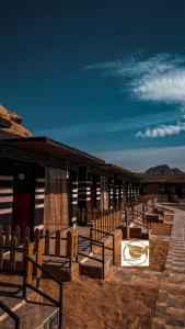 a row of wooden benches in front of a building at V D C Wadi Rum in Disah