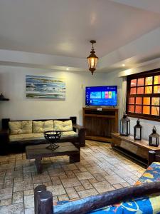 a living room with a couch and a flat screen tv at Pousada Alforria in Búzios