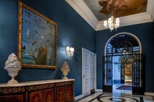 a hallway with a blue wall with a painting and a mirror at Hotel Palacio del Retiro, Autograph Collection in Madrid