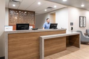 a man standing at a reception desk in a dental office at Candlewood Suites Sioux Falls, an IHG Hotel in Sioux Falls