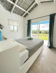 a white bedroom with a large bed and a large window at Finca Jasmat in Cabrera