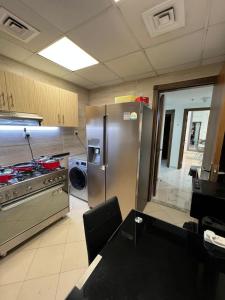 a kitchen with a stove and a stainless steel refrigerator at Ft 22 R1 Luxury Room attach bath Seaview Beach access Ajman غرفة فاخرة مع إطلالة على البحر وإمكانية الوصول إلى الشاطئ in Ajman 