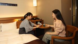 duas mulheres sentadas numa mesa num quarto de hotel em Urban Hotel Kyoto Shijo Premium em Quioto