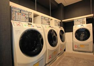 three washing machines are lined up in a laundry room at Urban Hotel Kyoto Shijo Premium in Kyoto