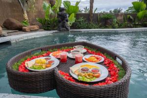une table avec des assiettes de nourriture au milieu d'une piscine dans l'établissement Sawah Sebatu Villa, à Ubud