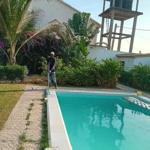 Ein Mann mit einem Roller, der neben einem Schwimmbad steht. in der Unterkunft Gambia Paradise in Tanji