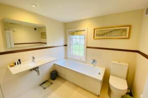 a bathroom with a tub and a sink and a toilet at Stunning 6-bed country house with heated pool in Headcorn