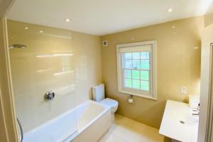a bathroom with a tub and a toilet and a sink at Stunning 6-bed country house with heated pool in Headcorn