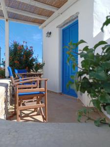 un porche con sillas y una puerta azul en Vicky's Studios, en Órmos Aiyialís