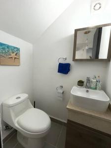a white bathroom with a toilet and a sink at Increíble Casa con alberca y club de playa in Barra Vieja