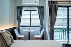 a hotel room with a bed and a table and chairs at College Haus Rangnam in Bangkok