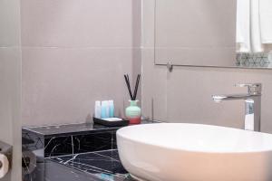 a bathroom with a white sink and a black counter at College Haus Rangnam in Bangkok
