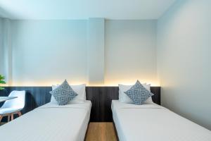 two beds in a room with a table and a chair at College Haus Rangnam in Bangkok +47 photos