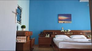 a blue bedroom with two beds and a blue wall at Compass in Kavála