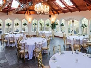 un salón de banquetes con mesas y sillas blancas y ventanas en Dalgarven Spa House, en Dalry