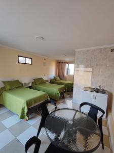 Habitación de hotel con 2 camas, mesa y silla en Hotel Brasil, en Antofagasta