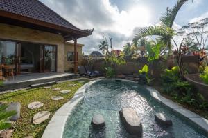 une piscine dans un jardin avec une maison dans l'établissement Sawah Sebatu Villa, à Ubud