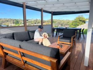 um homem sentado num sofá com um cão no pátio em Cosy Beach House - Near Hot Springs. em Tootgarook