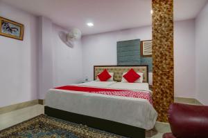 una camera da letto con un letto con cuscini rossi e una sedia di OYO Flagship Spc & Span a Jamshedpur