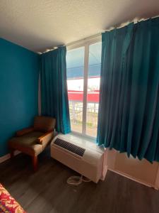 Schlafzimmer mit einem Fenster mit blauen Vorhängen und einem Ventilator in der Unterkunft Clover Inn and Suites in Shreveport